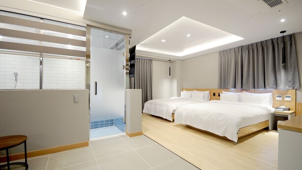 A modern hotel room with a large bed, a desk, and a bathroom with a shower. - Hound Hotel Gijang (Busan)