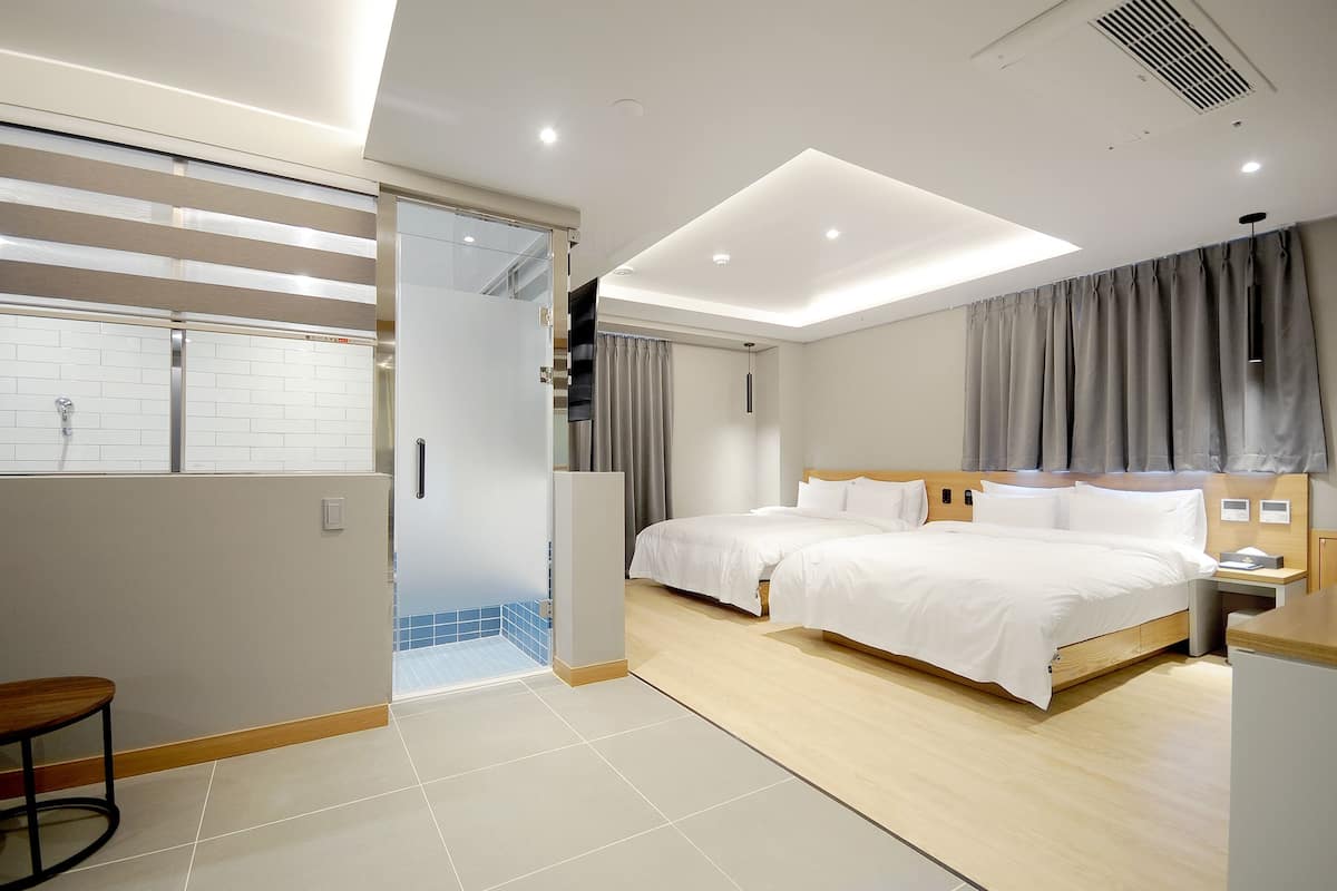 A modern hotel room with a large bed, a desk, and a bathroom with a shower.
