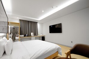 A modern hotel room with a large bed, a desk with a flat-screen TV, a wardrobe, and a seating area. - Hound Hotel Gijang (Busan)