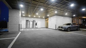 A parking garage with a car parked in one of the bays. - Hound Hotel Gijang (Busan)