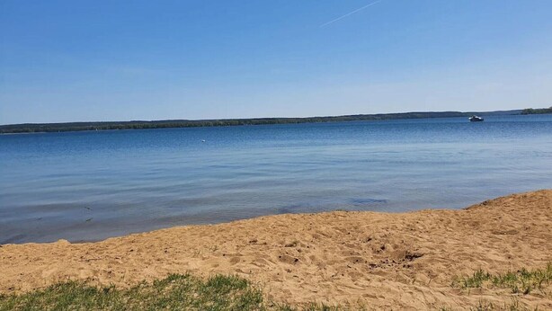 Ein Strand mit sandigem Ufer und ruhigem Wasser.
