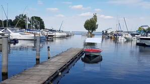 Ein Yachthafen mit Booten, die an Holzstegen festgemacht sind, ruhigem Wasser und einem Baum in der Mitte.