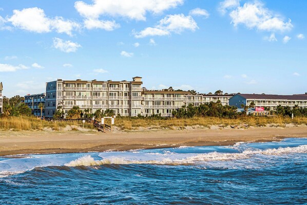 A beachfront hotel with multiple floors, balconies, and a beach view.