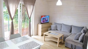 A cozy living room with a sofa, a coffee table, and a TV on a wooden cabinet. - Apartment in Dziwnów by Baltic Sea Beach (Dziwnow)