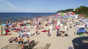 A crowded beach with numerous umbrellas and beachgoers.