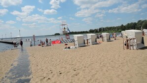 A beach with beach chairs, a lifeguard tower, and a pier.