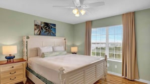 A bedroom with a bed, nightstands, a ceiling fan, a window with curtains, and a painting on the wall. - Key West Oasis! 2BR Villa with Pools and Marina at Coconut Mallory Resort (Key West)