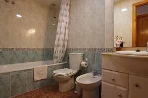 Een bad/douchecombinatie, een haardroger, een bidet, handdoeken