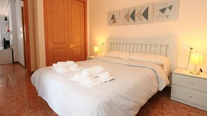 A hotel room with a large bed, a wooden door, and three wall-mounted artworks. - 001 - Altomar II 001 - comfortHOLIDAYS (Santa Pola)