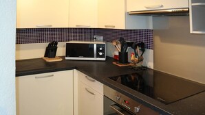 Cozinha equipada com micro-ondas, fogão e armários.