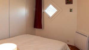 Quarto com cama, janela, radiador e luminária.