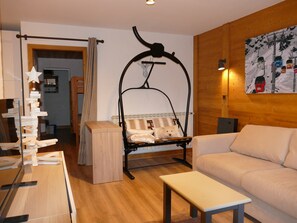 A cozy room with a wooden floor, a sofa, a bench, a hanging chair, and a star decoration on the wall.