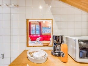A kitchen with a white tiled backsplash, a coffee maker, a toaster, a bowl of food, and a framed picture of a living room with a red sofa. - Chalet 5 bedrooms, 4 bathrooms, sauna in Tignes (Tignes)