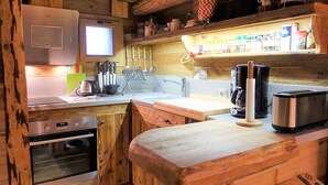 A compact kitchen with wooden cabinetry, a built-in oven, a coffee maker, and a toaster.