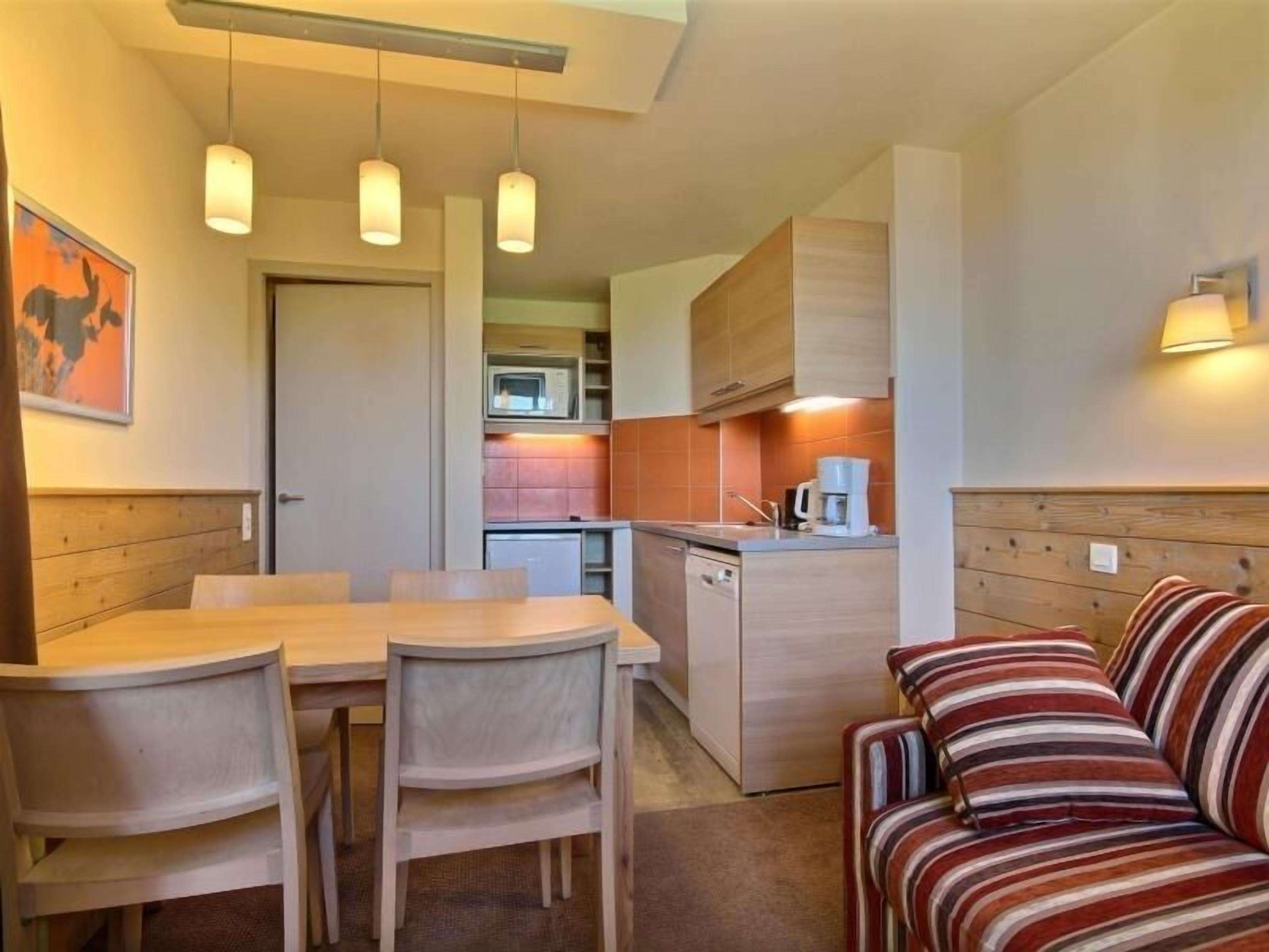 A compact living space with a dining area, kitchenette, and a sofa.