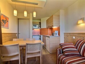 A compact living space with a dining area, kitchenette, and a sofa.