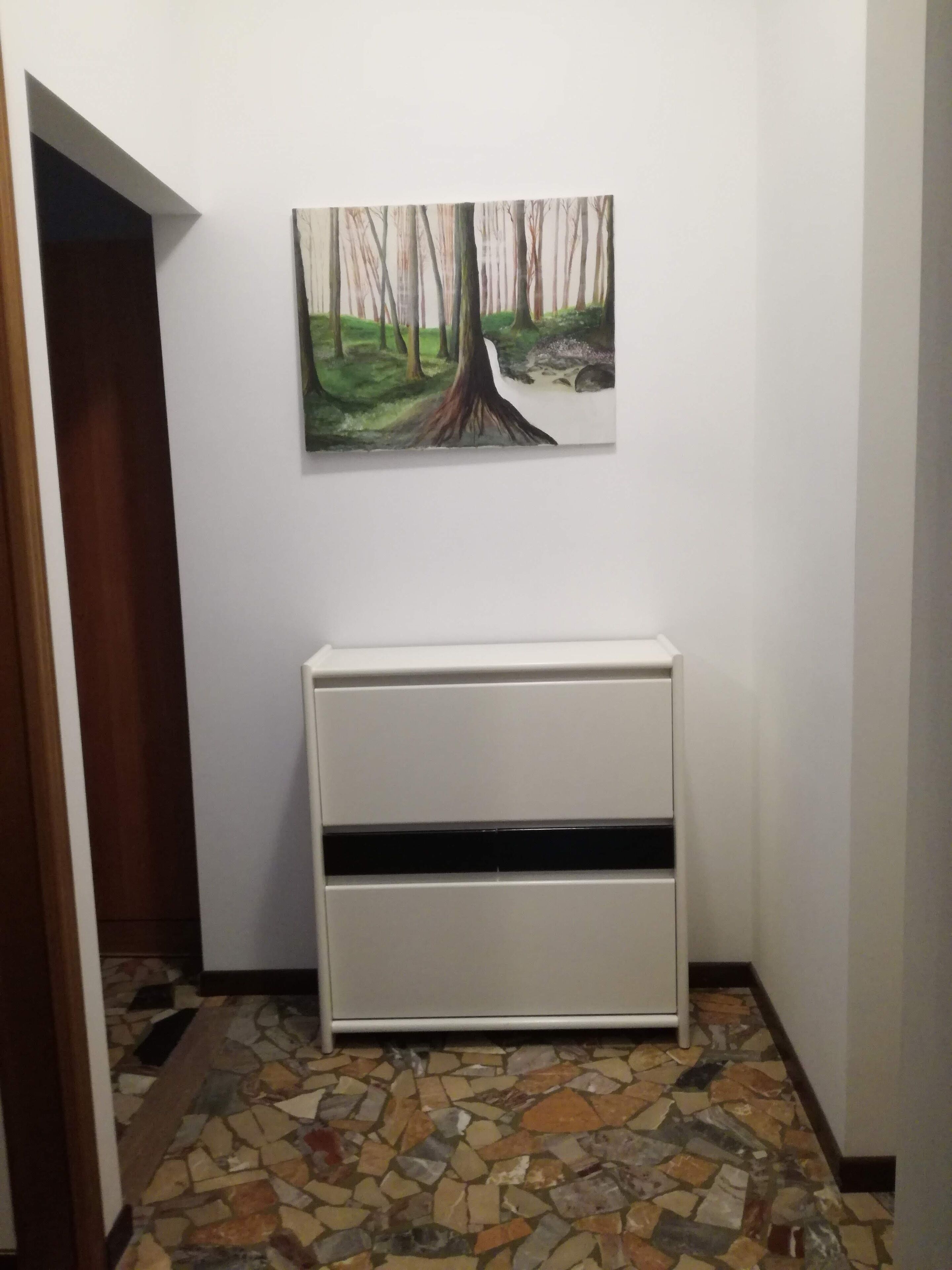 Ein Flur mit Mosaikboden, einem weißen Schrank und einem Wandbild einer Waldszene.