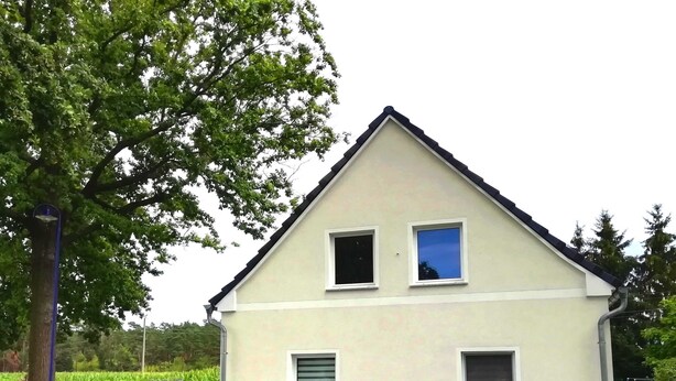 Ein zweistöckiges Haus mit Satteldach, zwei Fenstern im Obergeschoss und einer kleinen Veranda.
