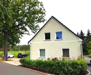 A two-story house with a gabled roof, two windows on the upper floor, and a small front porch.