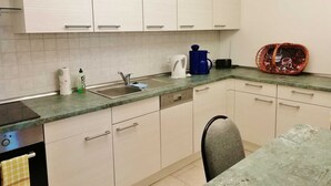 Eine kleine Küche mit weißen Schränken, einer Spüle, einer Kaffeemaschine und einem Korb auf der Arbeitsfläche.