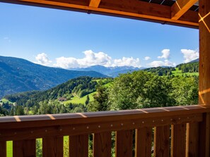 A wooden balcony with a view of a mountainous landscape.
