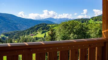 Un balcón de madera con vistas a un paisaje montañoso.