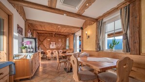 A rustic wooden interior with a dining area, wooden chairs, a table, and a refrigerator. - Comfortable Apartment “Treyer 3 Typ B” with Mountain View, Balcony & Garden (Terenten / Pustertal)