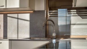 Eine moderne Küche mit Armatur aus Edelstahl, einer Glas Arbeitsplatte und Blick nach draußen durch ein Fenster.