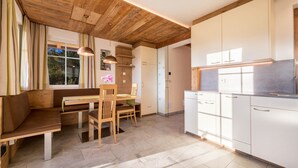 Une cuisine moderne avec des poutres en bois, un coin repas avec un banc et une vue sur la verdure environnante.