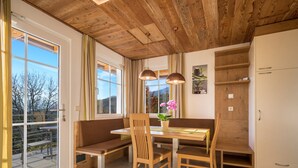 Ein Essbereich mit einer Holzbank, einem Holztisch und Pendelleuchten.