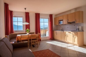 A kitchen with wooden cabinets, a microwave, and a dining area with a table and chairs.