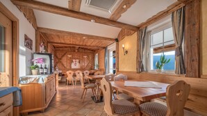 A wooden interior with a dining area, wooden chairs, a table, and a refrigerator. - Apartment “Treyer 1 Typ B” with Mountain View, Wi-Fi, Balcony & Garden (Terenten / Pustertal)