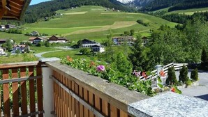 A mountain view with houses and a wooden balcony. - Apartment “Treyer 1 Typ B” with Mountain View, Wi-Fi, Balcony & Garden (Terenten / Pustertal)