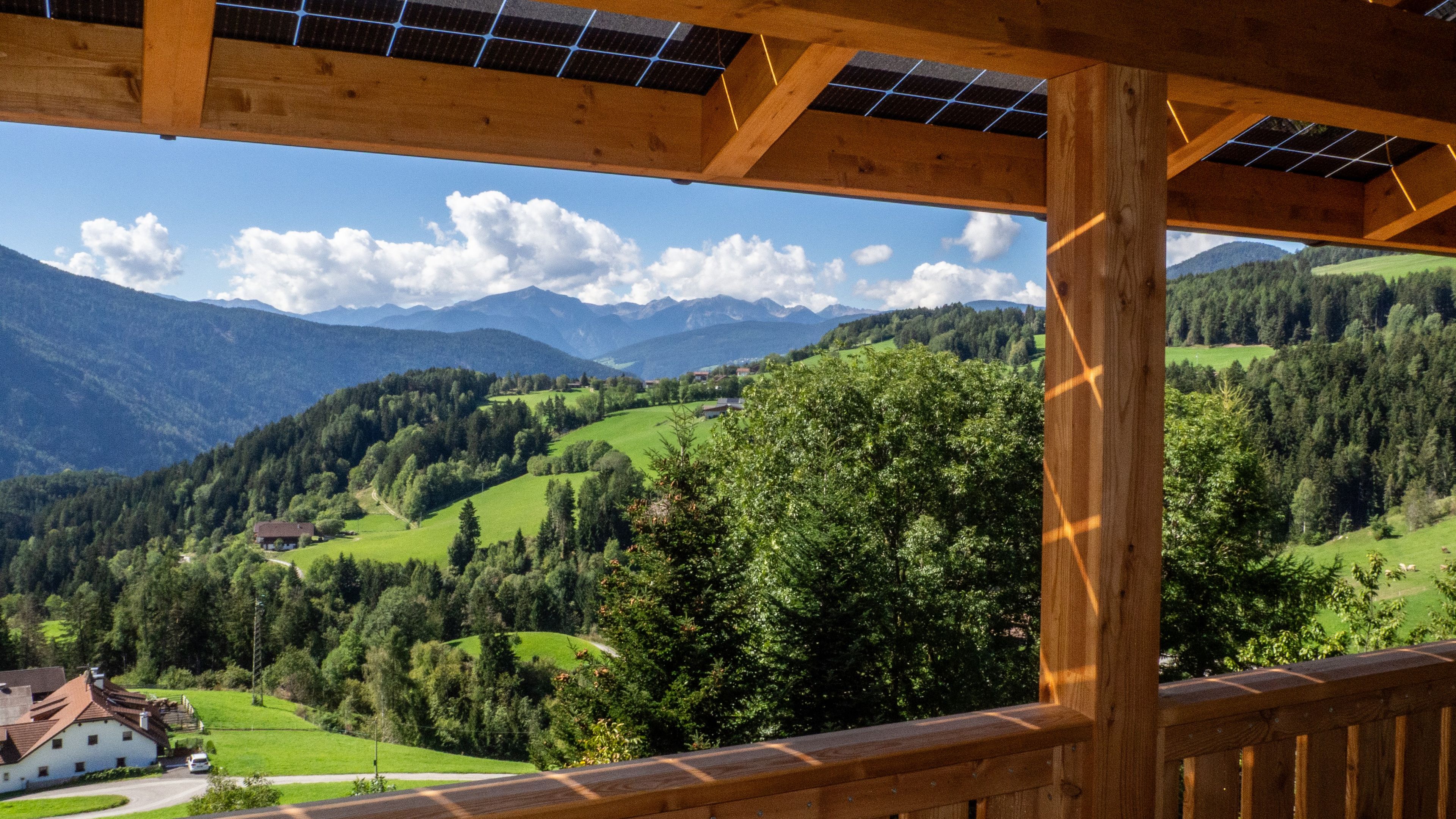 Un balcón de madera con vistas a un valle verde y montañas.