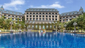 Un gran hotel con una piscina central, múltiples balcones y un estilo arquitectónico clásico.