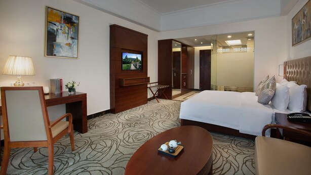 Una habitación de hotel con cama, escritorio, silla, televisor y mesa de centro.