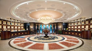 A grand lobby with a central circular marble floor, a chandelier, and a reception desk with framed artwork. - Wyndham Garden Haikou South (Haikou)