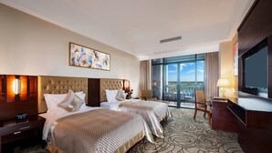 A hotel room with two beds, a large window with a view, a TV, and a desk with a lamp. - Wyndham Garden Haikou South (Haikou)