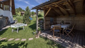 A wooden outdoor seating area with a table and chairs, a foosball table, and a covered patio.
