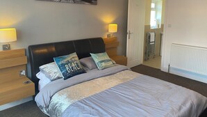 Ein Schlafzimmer mit einem Bett, zwei Nachttischen, einer Wandlampe, einer Tür und einem Heizkörper.