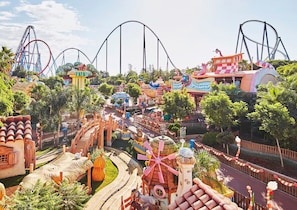 A theme park with roller coasters, a winding road, and various colorful buildings.
