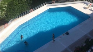 A rectangular swimming pool with clear blue water, surrounded by a concrete deck and a metal railing. - Beautiful apartment facing the sea (Mont-roig del Camp)