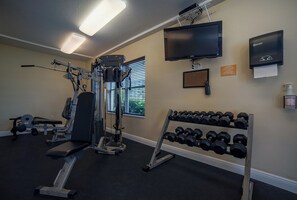 A gym with exercise equipment, a television, and a Bay West hand sanitizer dispenser. - 902 Sanibel - Oceanfront Panoramic Views (Daytona Beach Shores)