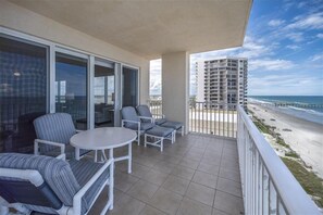 A balcony with a view of the beach and a high-rise building.