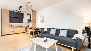 Moderni olohuone, jossa on harmaa sohva, puinen sohvapöytä ja ruokailutila, jossa on pöytä ja tuolit.