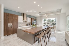 A modern kitchen with a large island, built-in cabinets, and a dining area with bar stools.