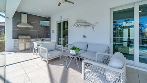 Un pati exterior modern amb una barbacoa, zona d'estar i una gran decoració de peix.