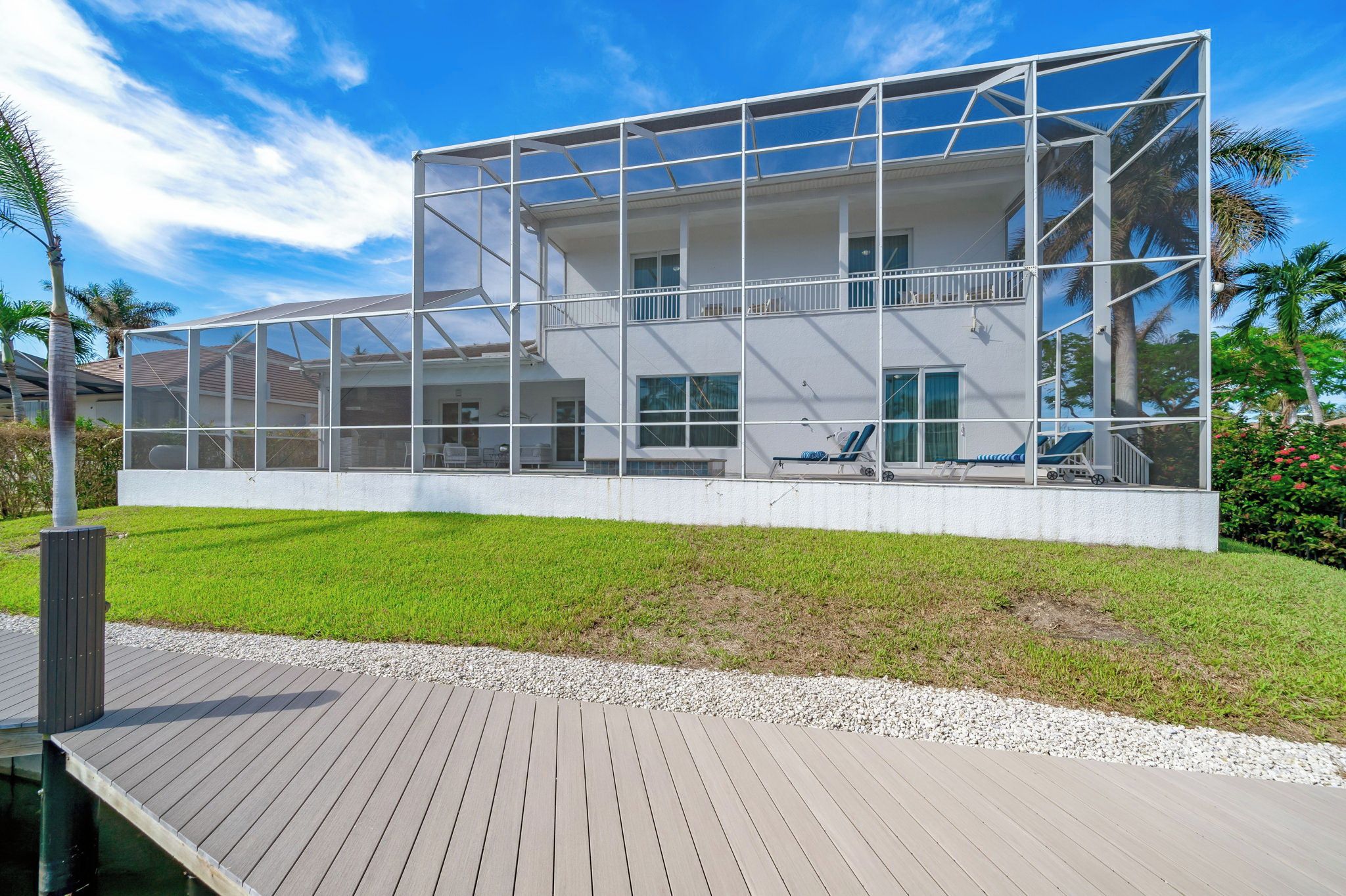 A modern house with a large deck, a swimming pool, and a well-maintained lawn.