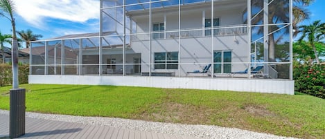 A modern house with a large deck, a swimming pool, and a well-maintained lawn.