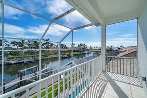Ein Balkon mit Blick auf einen Kanal, Palmen und Häuser im Hintergrund.